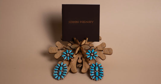 Turquoise stone earrings and a floral jewelry set displayed on a decorative wooden stand with branded packaging.