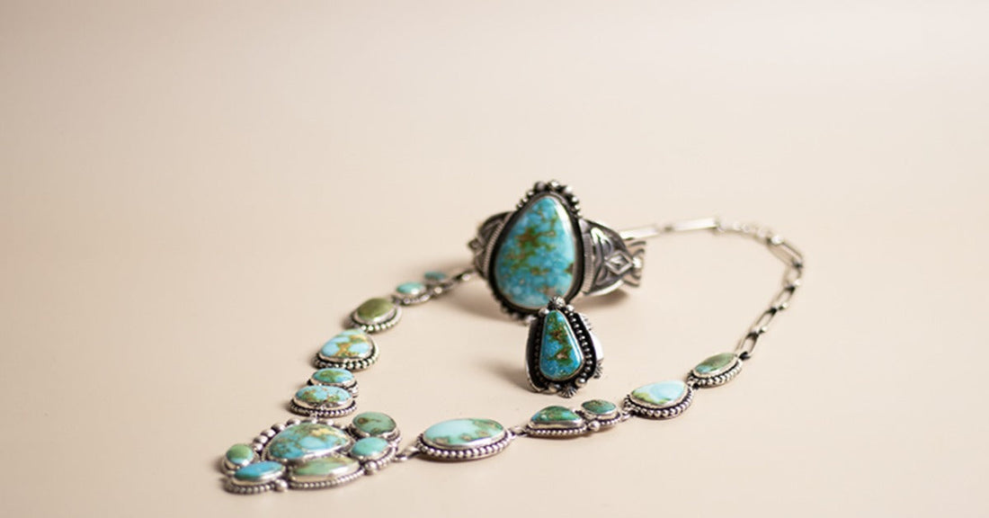 A turquoise jewelry set with a necklace, ring, and dangling earring arranged on a beige cloth surface.